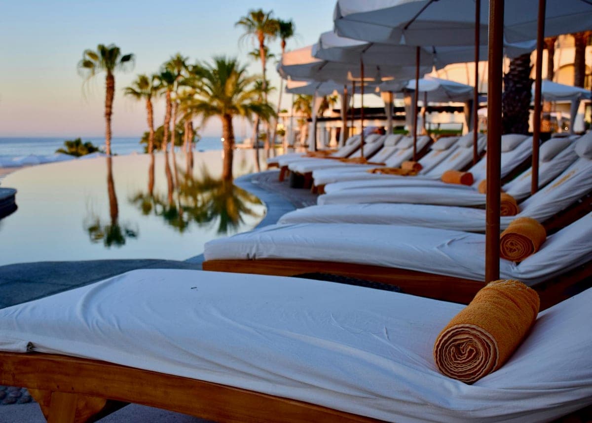 Infinity pool and lounge chairs at a recovery retreat during sunset