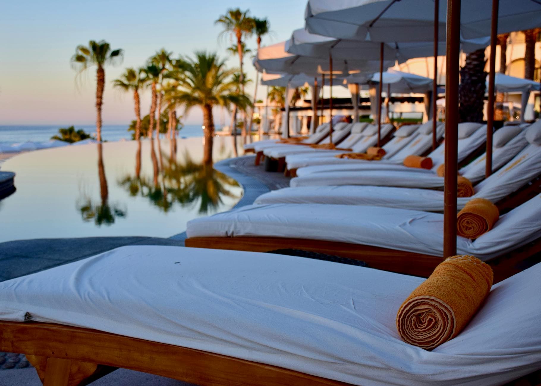 Infinity pool and lounge chairs at a recovery retreat during sunset