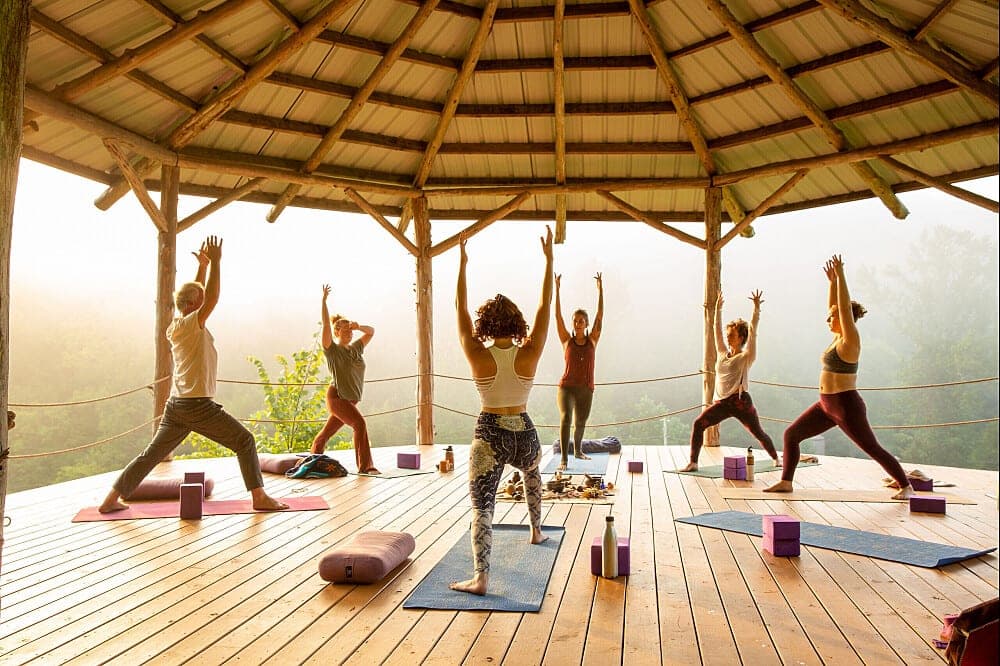 Group practising yoga together in an open-air pavilion at sunrise